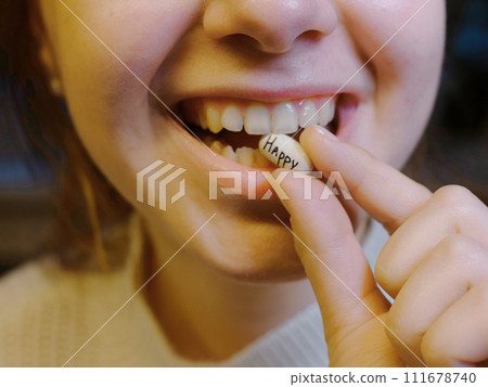 oval white tablet with the inscription happy in the mouth of a teenager 111678740