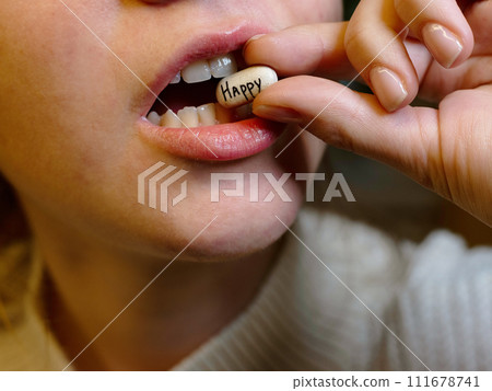 oval white tablet with the inscription happy in the mouth of a teenager 111678741