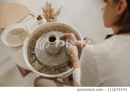 Close up of artisan's hands shaping clay bowl in pottery studio. Pottery art and creativity Close up of artisan's hands shaping clay bowl in pottery studio. Pottery art and creativity 111678743