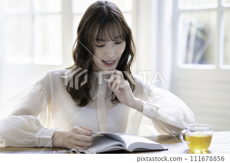 Woman reading by the window Woman reading by the window 111678856