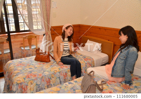 女孩旅行時，兩個年輕女子在飯店房間裡聊天 111680005