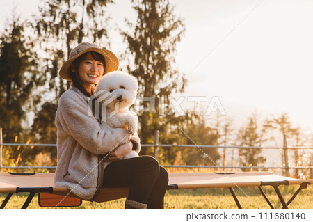 秋季和冬季在營地露營的亞洲女人抱著她的寵物狗 (Vision Frise) 秋季和冬季在營地露營的亞洲女人抱著她的寵物狗 (Vision Frise) 111680140