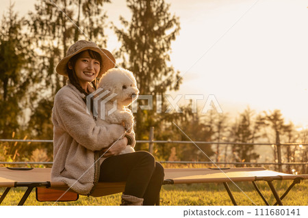 秋季和冬季在營地露營的亞洲女人抱著她的寵物狗 (Vision Frise) 111680141