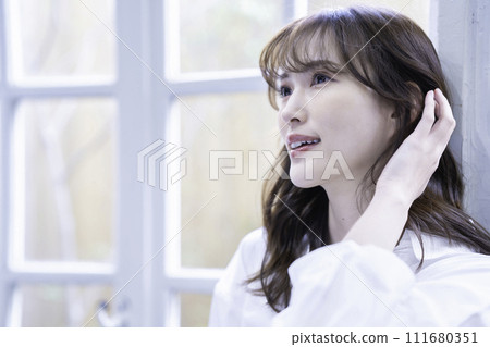 A feminine woman relaxing by the window 111680351