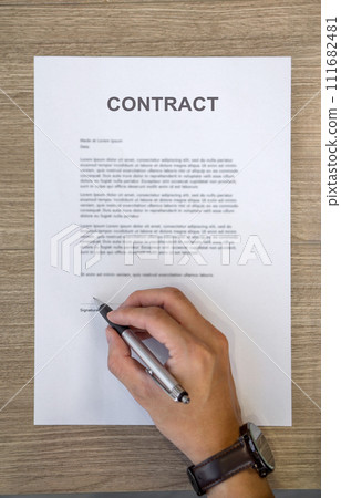 Closeup man hand holding a pen signing his name on a CONTRACT document. Top View 111682481
