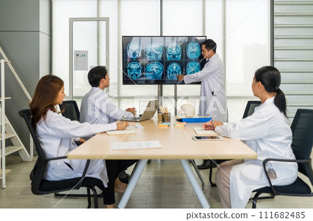 Group of doctor in white gown, discussing brain scans on large monitor in a meeting room. 111682485