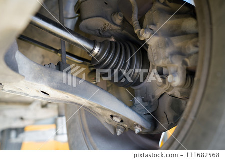 Closeup car's suspension system, focusing on the axle and CV joint area. 111682568