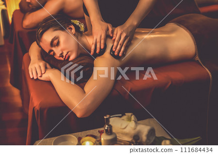 Hot stone massage at spa salon in luxury resort with warm candle light.Quiescent 111684434
