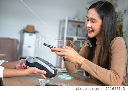 Young Asian woman smiling and paying with smartphone in restaurant 111685143