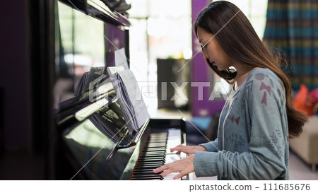 Young Asian pianist play piano in living room at home 111685676