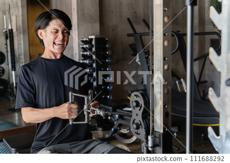 Young Asian man doing muscle training and working out at the gym/sports gym (back training/rowing) Young Asian man doing muscle training and working out at the gym/sports gym (back training/rowing) 111688292
