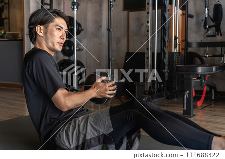 亞洲男子在健身房使用健身球進行腹部肌肉訓練(俄羅斯扭轉/扭轉緊縮) 亞洲男子在健身房使用健身球進行腹部肌肉訓練(俄羅斯扭轉/扭轉緊縮) 111688322