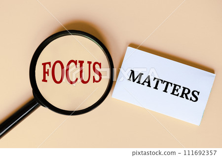 Top view of magnifying glass and notepad with text, Focus matters 111692357
