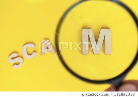 Top view of magnifying glass focusing on the work SCAM. Cyber crime concept 111692358