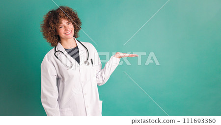 Cheerful woman doctor showing at blank green wall Cheerful woman doctor showing at blank green wall 111693360