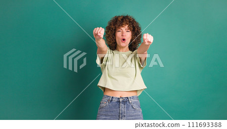 Excited young woman and smiling on green background Excited young woman and smiling on green background 111693388