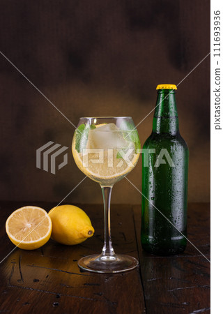 Cocktail in a wine glass. A glass of drink and a bottle nearby. Lemon slices and mint in a glass. Cocktail in a wine glass. A glass of drink and a bottle nearby. Lemon slices and mint in a glass. 111693936