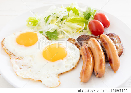 Delicious fried egg, sausage, bacon and vegetable salad for breakfast 111695131