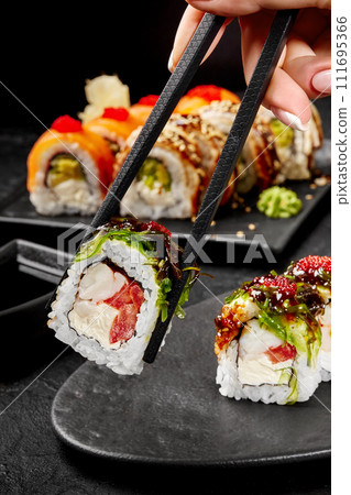Female hand taking sushi roll with crab meat by chopsticks 111695366