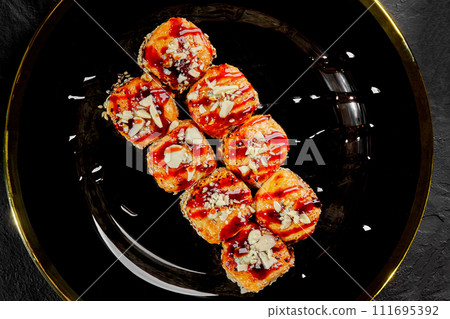 Baked sushi rolls with cheese caps on black and gold plate Baked sushi rolls with cheese caps on black and gold plate 111695392