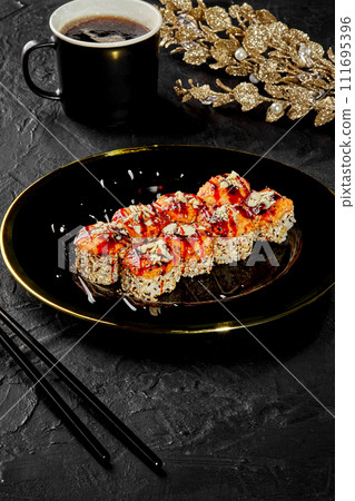 Baked sushi rolls on black platter with golden decor 111695396