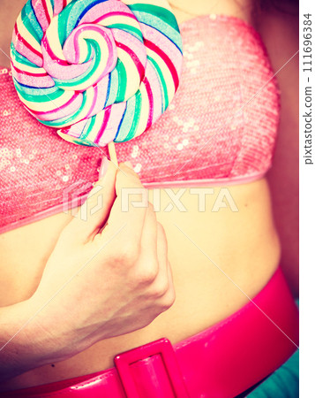 Woman holds colorful lollipop candy on breast 111696384