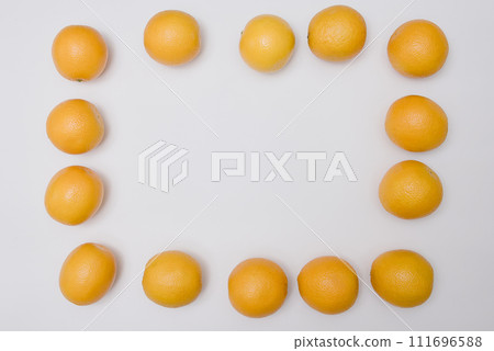 Ripe orange oranges are lined along the edge of the frame and form a frame for text or picture. 111696588