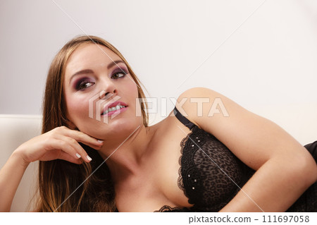 Woman lying in black lace lingerie on couch 111697058
