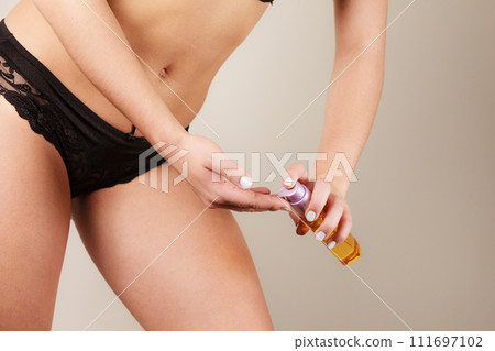 Woman applying moisturizing body oil lotion 111697102