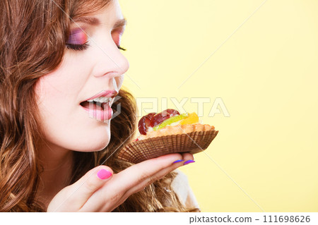 woman closed eyes holds cake in hand 111698626
