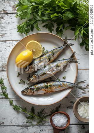 Sardines, lemon, greenery and salt on white plate on wooden kitchen table. Mediterranean cuisine 111698992