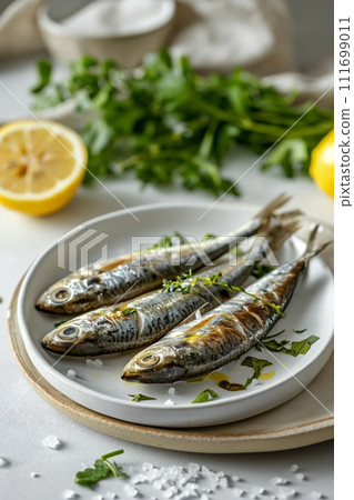 Sardines, lemon, greenery and salt on white plate on marble kitchen table. Mediterranean cuisine 111699011