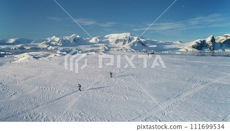 People running wild Antarctica snow trail race. Travel, active lifestyle, sport, recreation in Antarctic wild nature landscape. Snow covered mountains, icy ocean, sunny winter day. Aerial drone shot People running wild Antarctica snow trail race. Travel, active lifestyle, sport, recreation in Antarctic wild nature landscape. Snow covered mountains, icy ocean, sunny winter day. Aerial drone shot 111699534