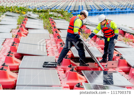 Side view of two professional technician workers hold solar cell panels with check problem during installation or set up to the system and they work over water reservoir area. 111700378