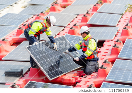 Close up two technician workers help to check and maintenance solar cell panels that set up over area of water reservoir. 111700389