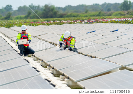 Side view of one technician worker sit and use laptop to work with co-worker who touch and check the problem of solar cell panel in the network system. 111700416