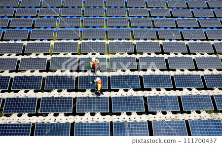 Top view and wind shot of two technician workers maintenance or check system of solar cell panels over the water reservoir as solar farm factory in concept of green energy for good environment. Top view and wind shot of two technician workers maintenance or check system of solar cell panels over the water reservoir as solar farm factory in concept of green energy for good environment. 111700437