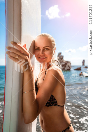 Woman sup sea travel in black bikini. Portrait of a happy girl on the background of a surfboard in the sea on a sunny summer day 111701235