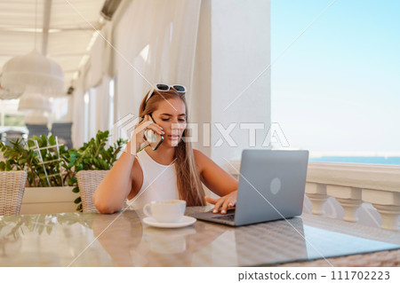 Woman coffee cafe laptop. Coffee break in cafe with sea view. Tranquil long haired woman drinking coffee in plant filled place. Woman sitting at a coffee shop with mobile phone drinking coffee. Woman coffee cafe laptop. Coffee break in cafe with sea view. Tranquil long haired woman drinking coffee in plant filled place. Woman sitting at a coffee shop with mobile phone drinking coffee. 111702223