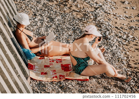 Woman reading book and Sitting on the Beach on Vacation. Summer Holidays Travel Concept. Summer chill. Rest and pleasure. Holidays on the beach. Side view 111702456