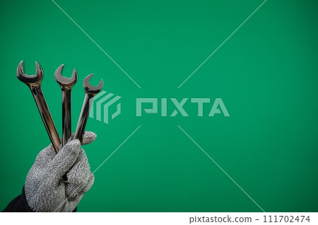 Man's hand holds a spanners isolated. Close up. High resolution product. High quality advertising Green background chromakey free space 111702474