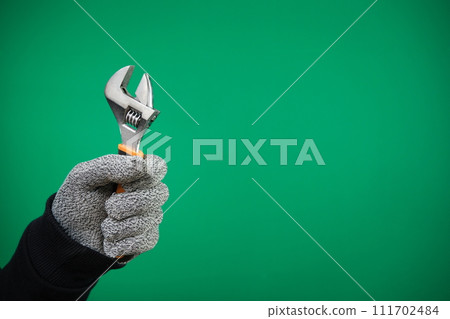 a worker advertising Green background chromakey builder, repairman, handyman, hands with protection glove holding wrench on white background. High quality a worker advertising Green background chromakey builder, repairman, handyman, hands with protection glove holding wrench on white background. High quality 111702484