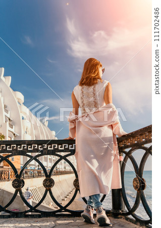 Woman summer travel sea. Happy tourist enjoy taking picture outdoors for memories. Carefree woman traveler posing on beach at sea on sunset, sharing travel adventure journey. Holiday vacation concept. Woman summer travel sea. Happy tourist enjoy taking picture outdoors for memories. Carefree woman traveler posing on beach at sea on sunset, sharing travel adventure journey. Holiday vacation concept. 111702486