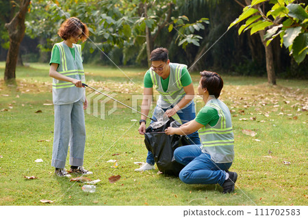Cheerful volunteers collecting garbage on college campus Cheerful volunteers collecting garbage on college campus 111702583