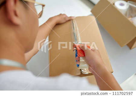 Volunteer sealing cardboard box with food and necessities 111702597