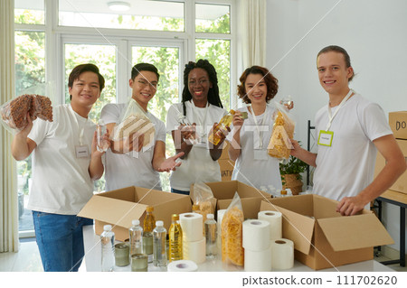 Group of happy volunteers packing food donated for people in need 111702620