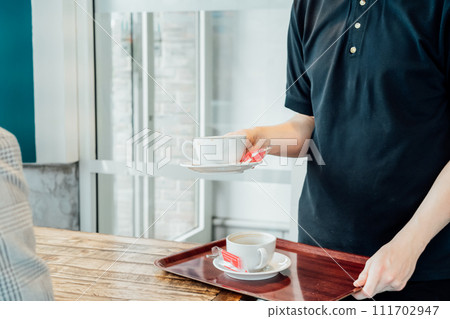 Waiter removing dirty dishes from the tables in cafe. Waiter hand pick up dirty coffee cups. Service job in cafes. Occupation and work concept. Part-time work for youth. Problems of unemployment 111702947
