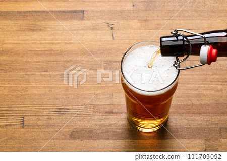 Pouring craft beer into pint glass on a wooden table 111703092