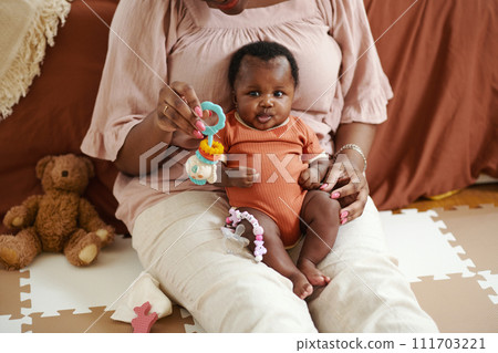 Cropped image of mother sitting on floor and playing with baby girl 111703221
