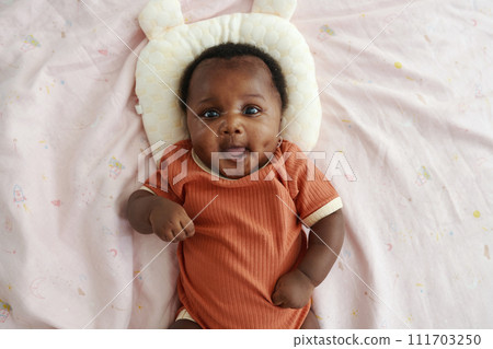 Portrait of Black newborn girl lying on bed with baby pillow, top view 111703250